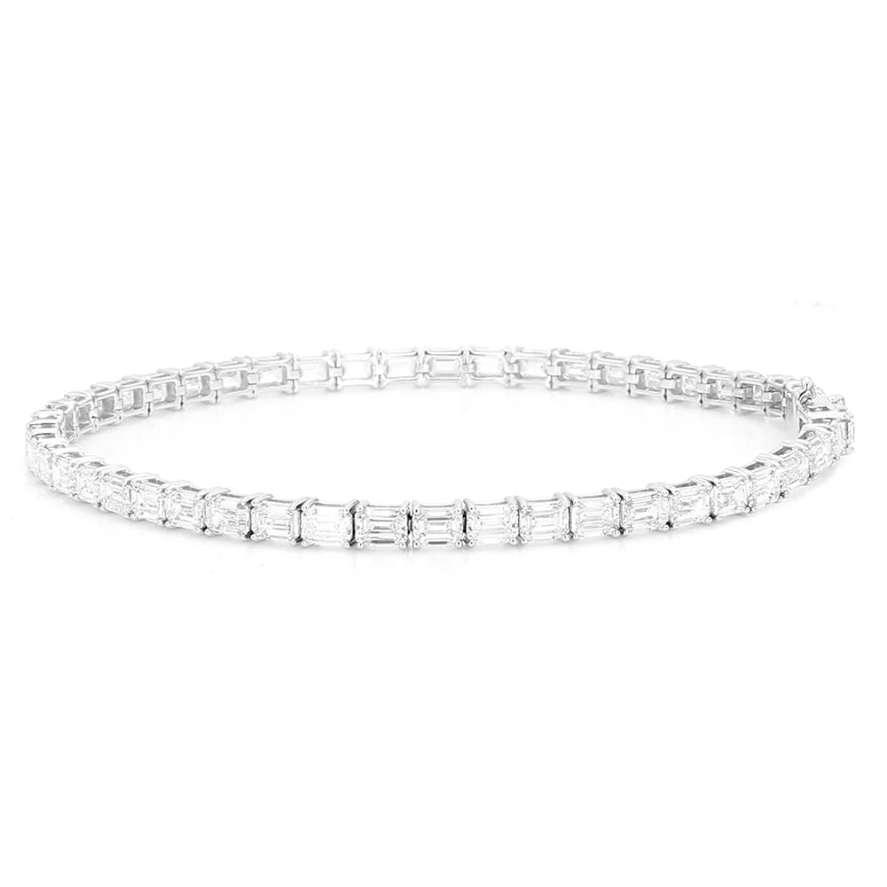 A silver tennis bracelet featuring a continuous row of baguette-cut clear gemstones in a prong setting, displayed against a solid white background.