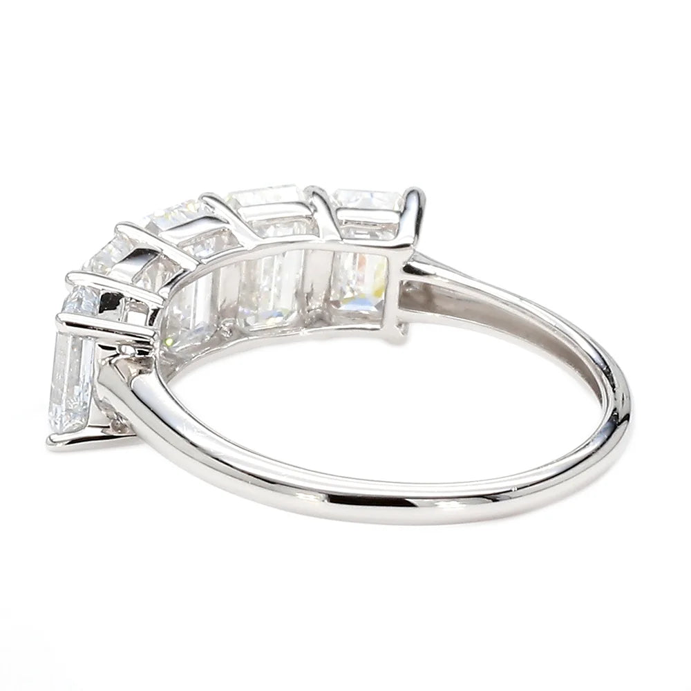 A silver-colored ring featuring a row of baguette-cut clear gemstones in a prong setting, shown on a plain white background.