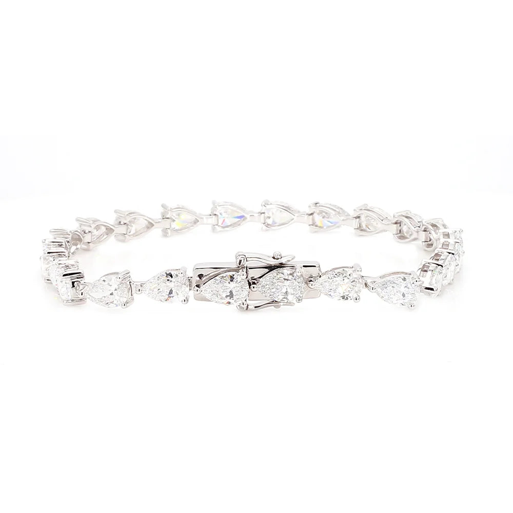 A silver tennis bracelet featuring a continuous link design with pear-cut and heart-shaped clear gemstones, displayed on a solid white background.