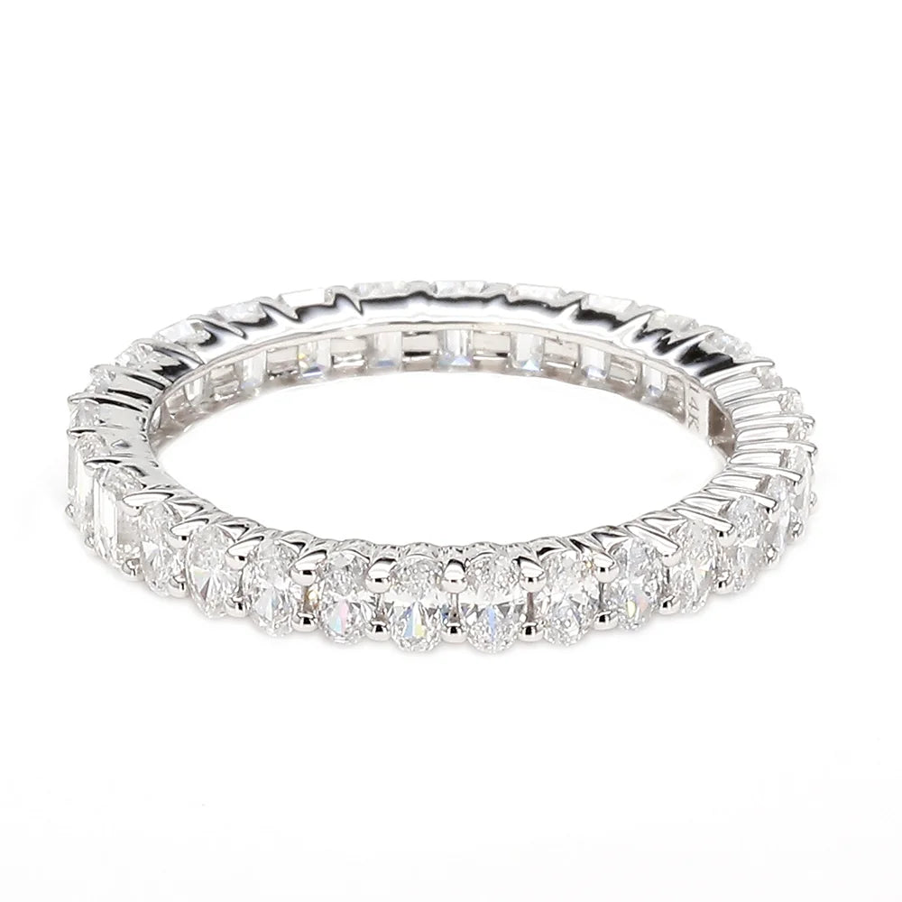 A silver-toned eternity ring featuring a continuous line of baguette and round-cut clear gemstones, photographed on a seamless white background.